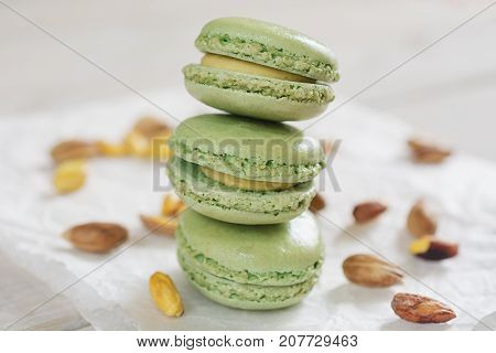 Peeled and unpeeled pistachio nuts and pistachio flavored macarons presented on a white napkin presented