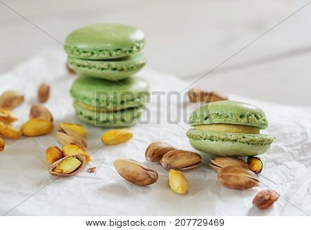 Peeled and unpeeled pistachio nuts and pistachio flavored macarons presented on a white napkin presented