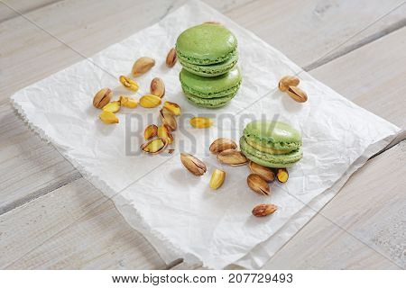 Peeled and unpeeled pistachio nuts and pistachio flavored macarons presented on a white napkin presented
