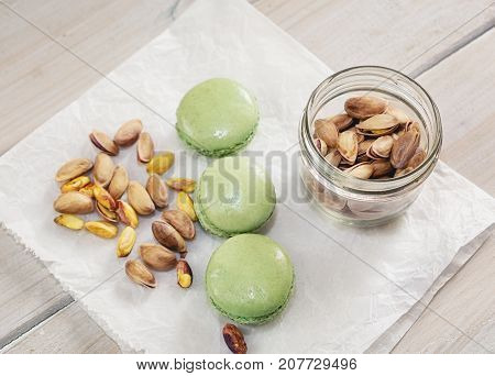 Peeled and unpeeled pistachio nuts and pistachio flavored macarons presented on a white napkin presented