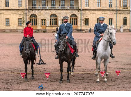 Gatchina St. Petersburg Russia - September 30 2017: Horse show of Cossacks on the parade ground of the Gatchina Palace. Three Cossack riders stand in front of the audience.