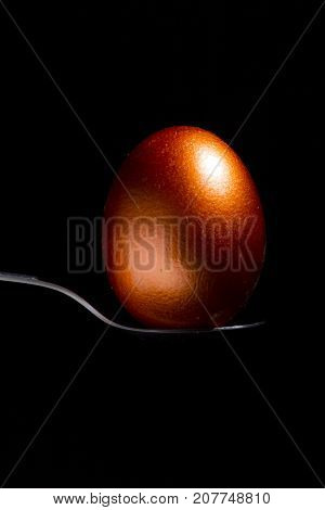 bronze egg on a spoon on a black background