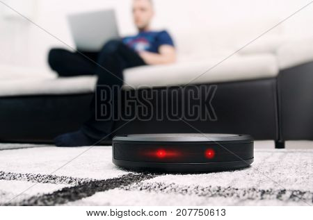 Robotic vacuum cleaner working on carpet. Abstract science fiction red eyes sensor concept