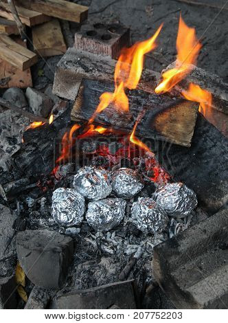 A camp fire with potatoes roasting in aluminium foil in the hot coals. Campfire cooking is one of the great things about camping.