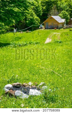 A Stone Fireplace In Front Of A Wooden House In The Forest.