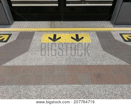 Black arrows on yellow sign background in front of automatic door exit and entrance on train transportation