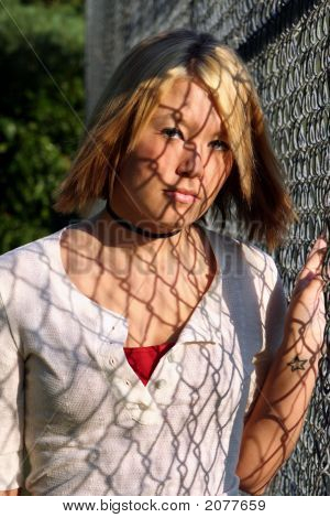 Jonge blonde vrouw met hek schaduwen