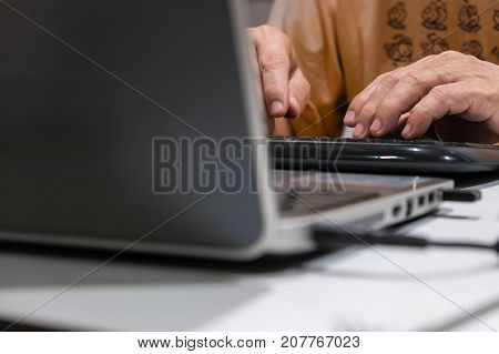 A man types keyboard in front of the notebook computer.