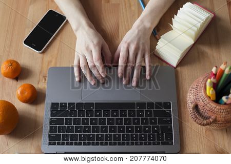 Girl's hands on a modern lapop - top view