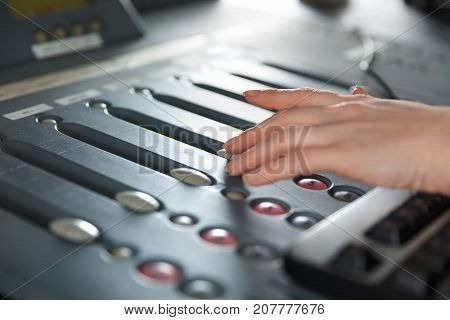 Female radio host using adusting volume at music mixer in radio studio