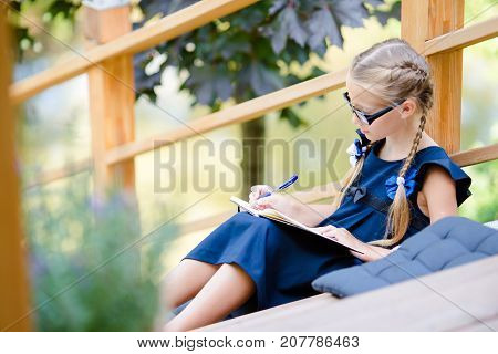 Adorable little school girl with notes and pencils outdoor.