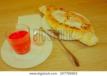 Khachapuri on ajarski - recipe of Georgian cuisine. Adjarian Georgian national dish Khachapuri bread with cheese and egg on a plate in a cafe - Retro color