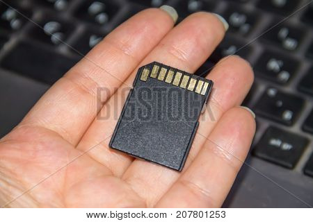 Hand Holding Sd Card On Laptop Background