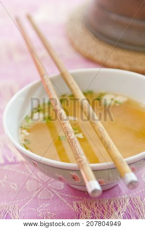 Close-up of chopsticks resting on bowl of miso soup. Shallow depth of field with focus on the middle of the chopsticks.