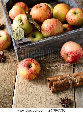 Box with ripe apples and cinnamom on wooden background. Copy-space
