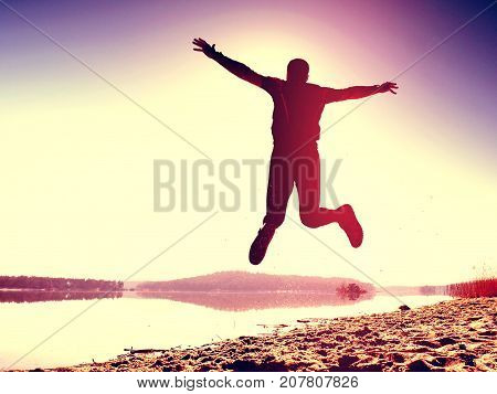 Jumping Man. Sportsman Crazy Jumping  And Jogging On Beach During The Sunrise