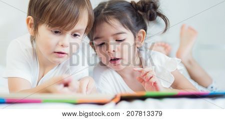 Brothers and sister read a bedtime story togather on the bed in bedroom kid child family study education and home work concept