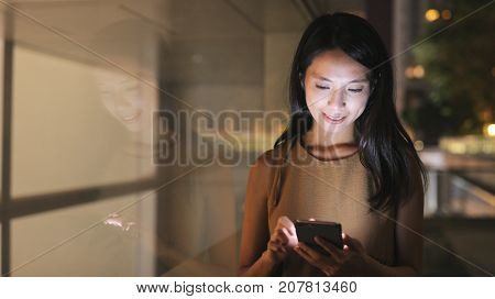Woman looking at mobile phone in city at night 
