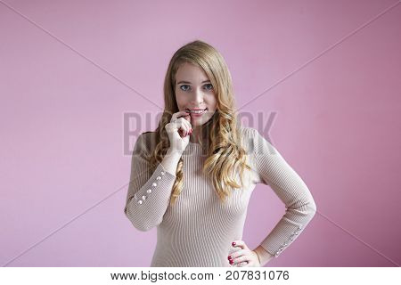 Oops. Beautiful girl with curly hair touching her lips and smiling guiltily at camera feeling ashamed after she did something wrong. Human facial expressions emotions feelings and reaction