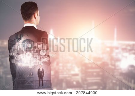 Back view of thoughtful young businessman standing on abstract city backgroound with digital business hologram and copy space. Technology concept. Double exposure
