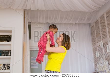 happy family. Mother throws up baby, playing at home.