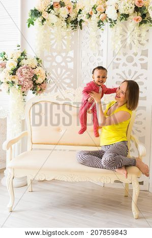 Smiling Mother Playing With Baby Son At Home