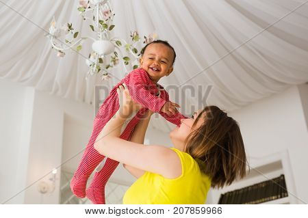 happy family. Mother throws up baby, playing at home.