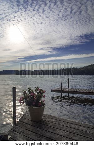 Dock with potted flowers on lake; cirrocumulus or popcorn clouds in blue sky