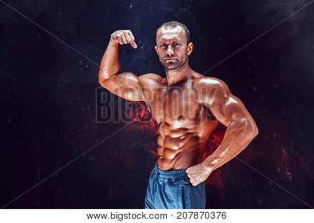 Strong bald bodybuilder with six pack. Strong bodybuilder man with perfect abs, shoulders, biceps, triceps and chest, personal fitness trainer flexing his muscles