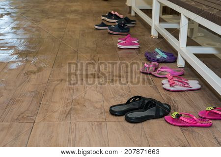 Children flip flops on the wooden background by swimming pool