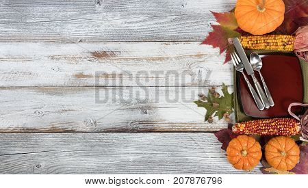 Dinner setting with autumn foliage pumpkins gourds corn and acorns for Thanksgiving and fall holidays