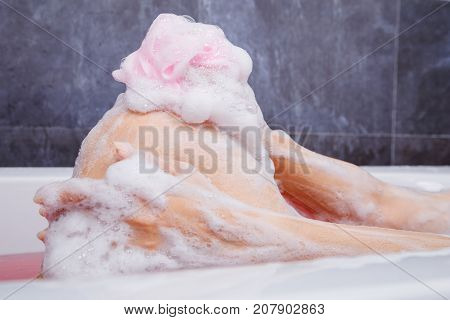Close Up Of Woman Washing Knee With Pink Sponge In Bathtub