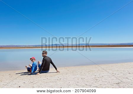 family of two father and son ready to swim in salty cejar lagoon in atacama desert chile healthy active family lifestyle and vacation concept