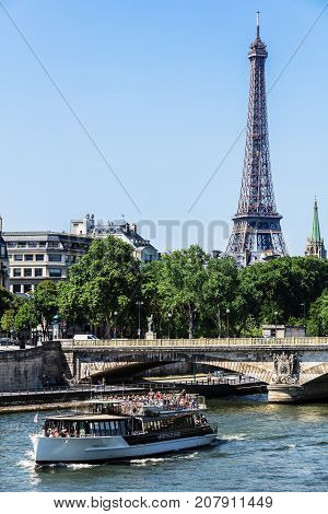 Paris France - July 07 2017: Tourists watch the sights of Paris from the River Seine by a cruise tourist ship. The Invalides Bridge (Pont des Invalides) and the Eiffel Tower in the background.