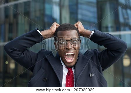 Outdoor Image Of Emotional African Male Wearing Formal Clothes And Eyeglasses Staring At Camera With