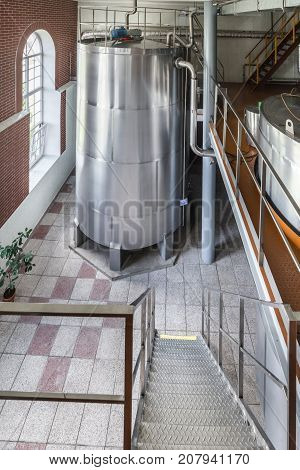A large room with an installed metal cistern. Equipment for mixing sugar and yeast mixture.