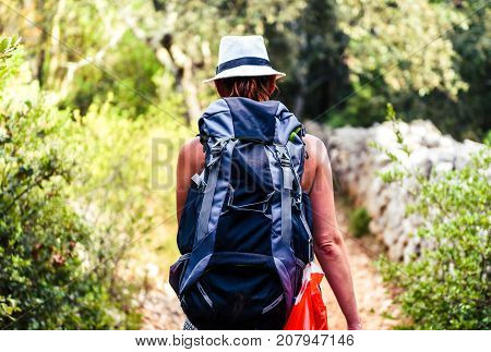 Woman Hiking On Country Footpath With Rock Fence And Woods.