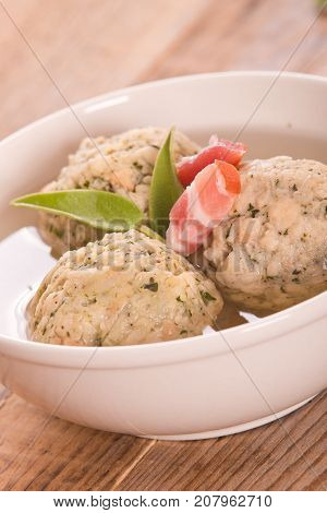 Canederli pasta with bacon on wooden table.