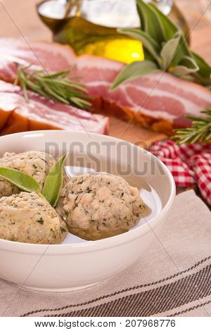 Canederli pasta with bacon on wooden table.
