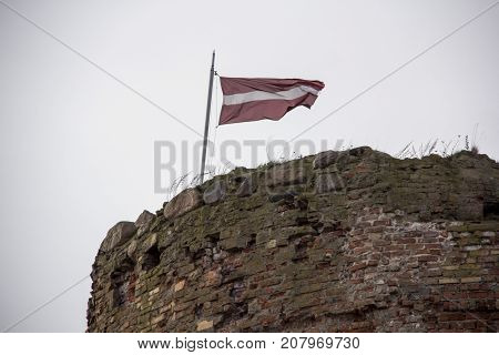 The ruins of the Livonia Order Castle was built in the middle of the 15th century. Bauska Latvia in autumn. Latvian flag on the top of the tower