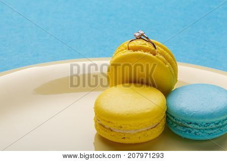 ring in makarun on the yellow plate over blue background. the offer to marry. place for text