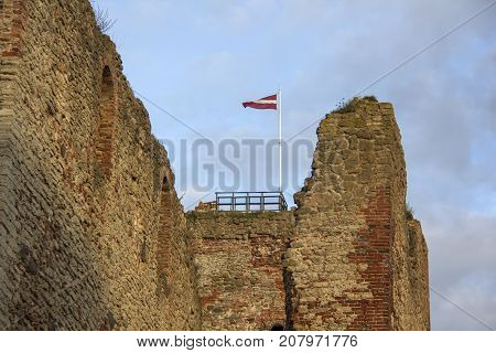 The ruins of the Livonia Order Castle was built in the middle of the 15th century. Bauska Latvia in autumn. Latvian flag on the top of the tower