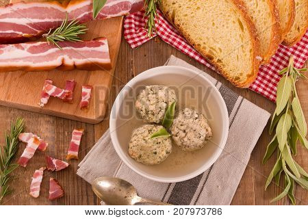 Canederli pasta with bacon on wooden table.