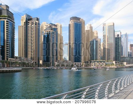 High houses in bright blue and beige tones reflected in the waters of the canal in Dubai