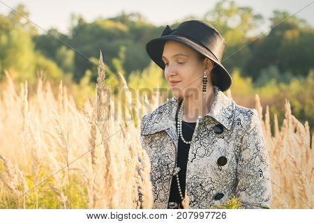 attractive young luxury woman walking at autumn dry grass