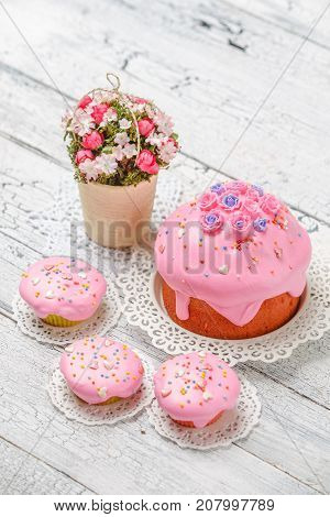 Traditional Easter cake with decorations and cupcakes on wooden table