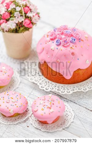 Traditional Easter cake with decorations and cupcakes on wooden table