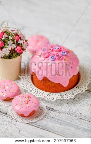 Traditional Easter cake with decorations and cupcakes on wooden table