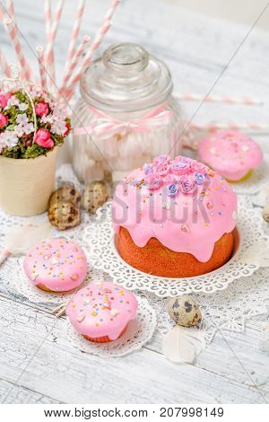 Traditional Easter cake with decorations and cupcakes on wooden table