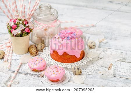 Traditional Easter cake with decorations and cupcakes on wooden table